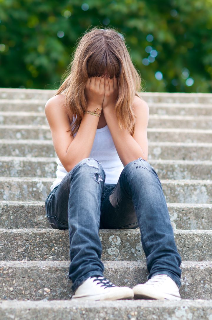 Sad teenage girl sitting alone on the stairs.