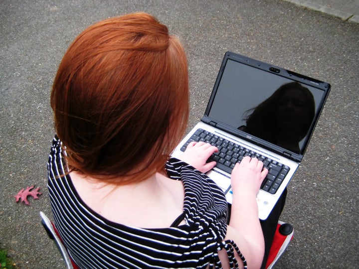 Woman and her Reflection on Laptop as she sends her email across the internet with wireless technology.