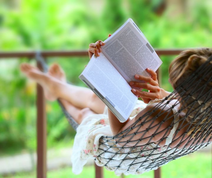 Young woman reading a book lying in hammock