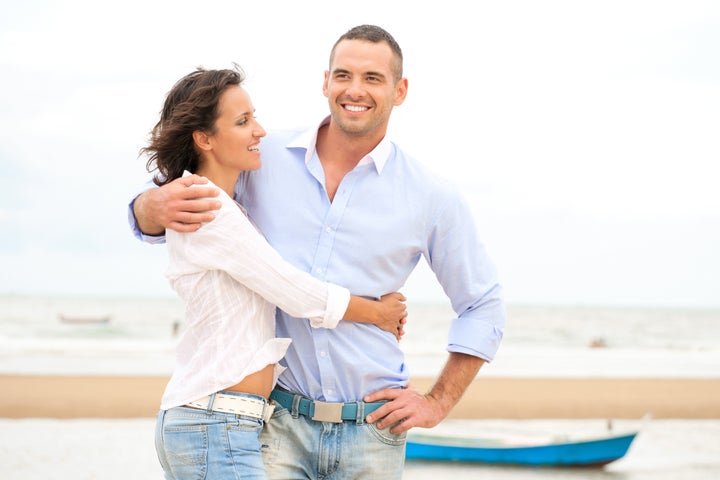 Portrait of a happy young couple having fun at the sea shore