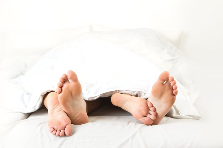 Foot of two people in the bedroom, on white background