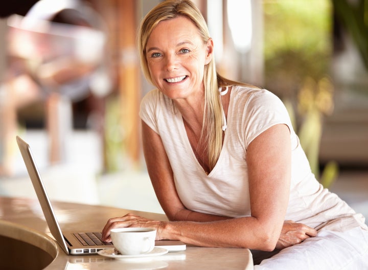 Beautiful mature woman smiling while using laptop at the hotel lobby