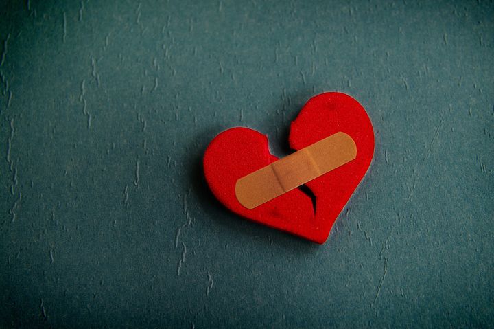 red broken heart with a bandage, on textured blue