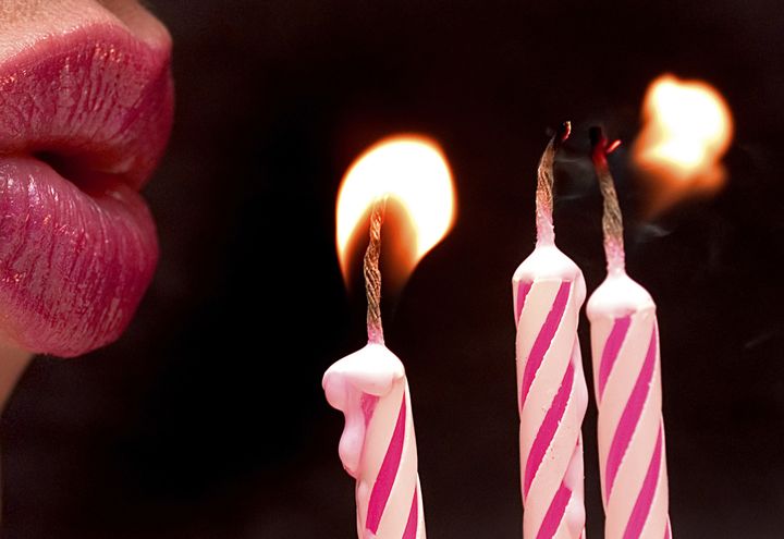close-up of lips blowing out pink candles