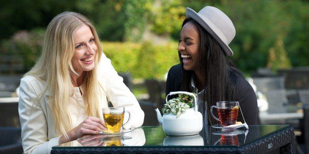 Women friends laughing and enjoying their tea outdoors