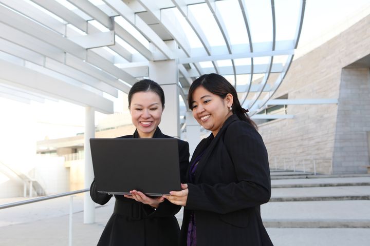 Two diverse business woman at office building with laptop computer