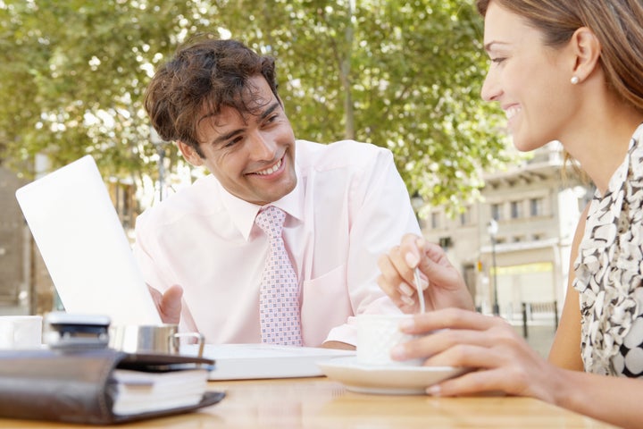 Business people having a coffee in a coffee shop terrace, having a meeting and using a laptop computer.