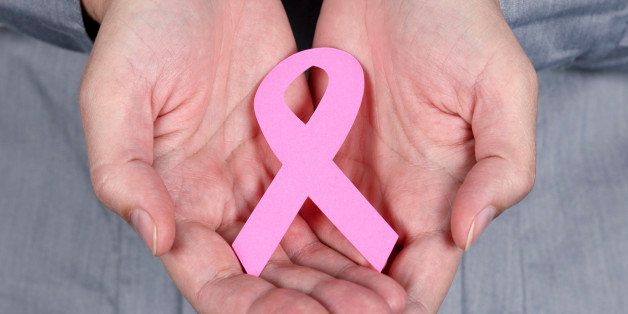 Woman holding breast cancer ribbon symbol in her hands.