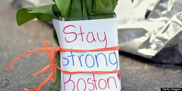 Flowers and a message are left on Newbury Street April 16, 2013 in Boston, Massachusetts, a few blocks from where two explosions struck near the finish line of the Boston Marathon on Monday. Three people, including a child, were killed and more than 170 were injured in the explosions that occurred a few seconds apart near the finish line of the 117th rendition of the world's oldest international marathon. AFP PHOTO/Stan HONDA (Photo credit should read STAN HONDA/AFP/Getty Images)