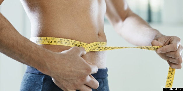 cropped view of caucasian young man measuring waist with yellow tape. Horizontal shape, mid section, side view