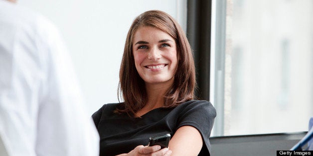 Smiling and Happy Business woman sitting at a corporate table with other Business men and conducting a group meeting to discuss teamwork strategy for Big Business decisions.