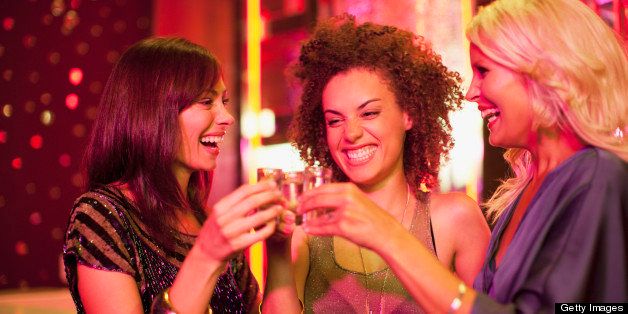 Friends toasting shot glasses in nightclub