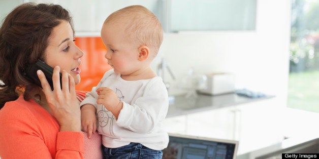 Mother holding baby and talking on cell phone