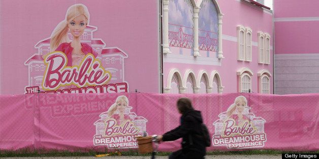 BERLIN, GERMANY - APRIL 23: A woman rides a bicycle past the construction site of the Barbie Dreamhouse Experience on April 23, 2013 in Berlin, Germany. The Barbie Dreamhouse Experience is a 2,500 square meter structure meant to show Barbie's ideal house in life scale and will offer interactive tours and other experiences. The house is scheduled to open to the public on May 16. (Photo by Sean Gallup/Getty Images)