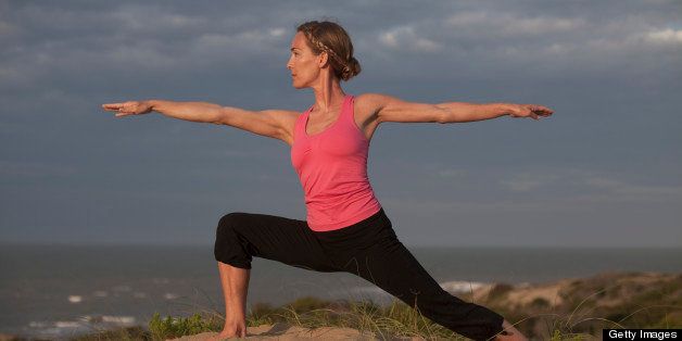 woman practicing yoga in the dunes at sunset