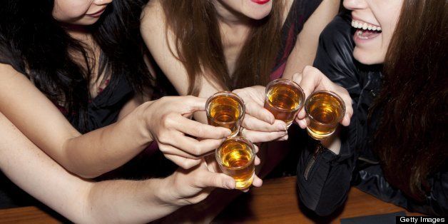 Women friends toasting with shots at a bar