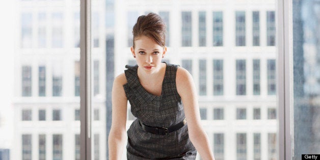 Businesswoman leaning on desk in office