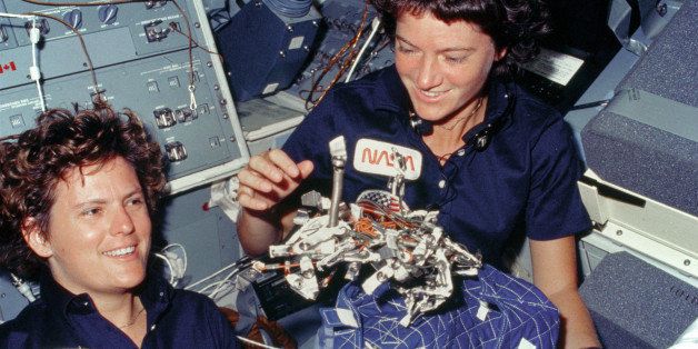 Astronauts Kathryn D. Sullivan, left, and Sally K. Ride display a 'bag of worms.' The 'bag' is a sleep restraint and the majority of the 'worms' are springs and clips used with the sleep restraint in its normal application. Clamps, a bungee cord and velcro