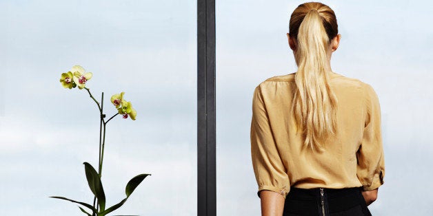 Businesswoman sitting on desk looking out window