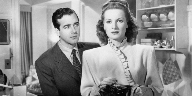 John Payne stands in back of Maureen O'Hara as she holds a coffee pot in a scene from the film 'Miracle On 34th Street', 1947