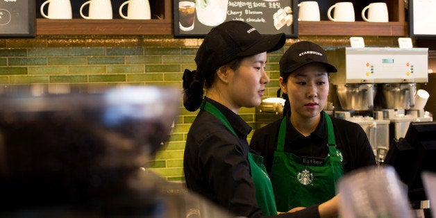 Barista Kim Jung Mi, a mother who had left the workforce seven years ago and is now employed by Starbucks Coffee Korea Co. under its 'returning-mom' program, right, works behind the counter with a colleague at one of the company's stores in Gimpo, South Korea, on Friday, March 7, 2014. Starbucks Korea's 'returning-mom' program is part of a drive to raise female participation in Asia's fourth-largest economy as the nation's first female leader, President Park Geun Hye, tries to counter the effects of an aging population. Photographer: SeongJoon Cho/Bloomberg via Getty Images 