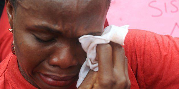 One of the mothers of the missing Chibok school girls wipes her tears as she cries during a rally by civil society groups pressing for the release of the girls in Abuja on May 6, 2014, ahead of World Economic Forum. Members of civil society groups marched through the streets of Abuja and to the Nigerian defence headquarters to meet with military chiefs, to press for the release of more than 200 Chibok school girls abducted three weeks ago. Suspected Boko Haram Islamists have kidnapped eight more girls from Nigeria's embattled northeast, residents said on May 6, after the extremist group's leader claimed responsibility for abducting more than 200 schoolgirls last month and said in a video he was holding them as 'slaves' and threatened to 'sell them in the market'. AFP PHOTO/PIUS UTOMI EKPEI (Photo credit should read PIUS UTOMI EKPEI/AFP/Getty Images)