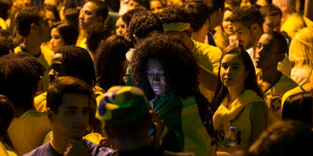 BELO HORIZONTE, BRAZIL - JUNE 23: A fan of the Brazilian football team checks her phone at half-time in their match against Cameroon in the Savassi neighbourhood on June 23, 2014 in Belo Horizonte, Brazil. Brazil, the host nation of the 2014 FIFA World Cup, finished top of Group A which results in a fixture against Chile in the 'Round of 16'. (Photo by Oli Scarff/Getty Images)