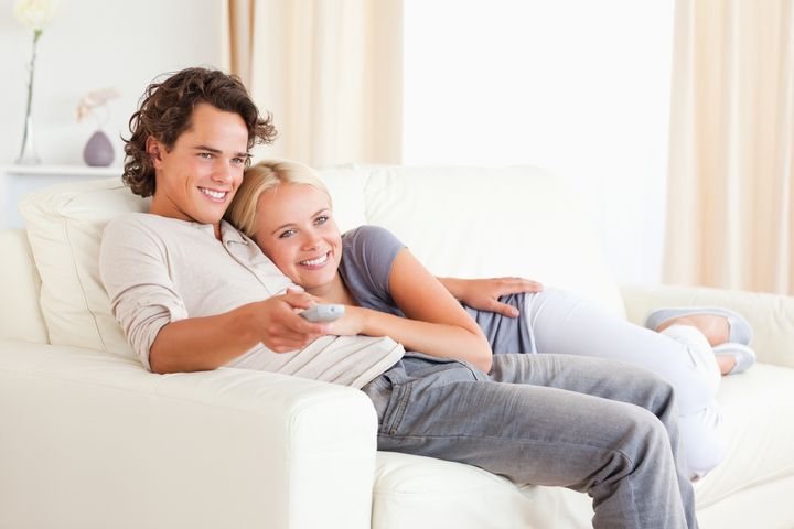Couple cuddling while watching TV in their living room