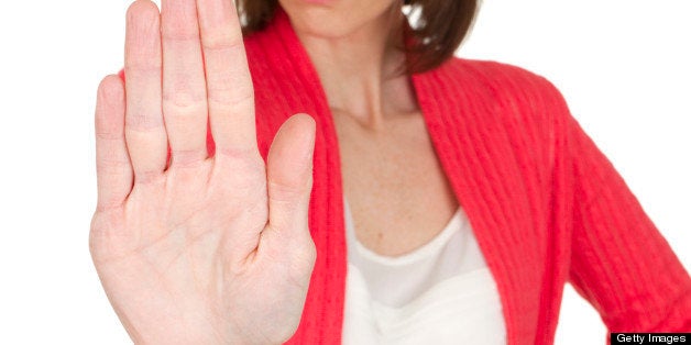 mid adult woman holding hand out as a stop sign isolated on white