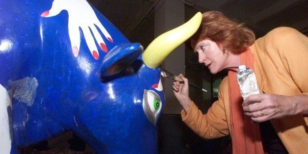 Artist Edwina Sandys, the grand-daughter of Winston Churchill, helps to repair minor damage with a little touch up paint on her CowParade cow "Cow Hands" Wednesday, Sept. 20, 2000, in New York. A few weeks ago, two people tried to steal her cow, which is one of the cows that will be sold at a benefit auction Sept. 28. (AP Photo/Ed Bailey)