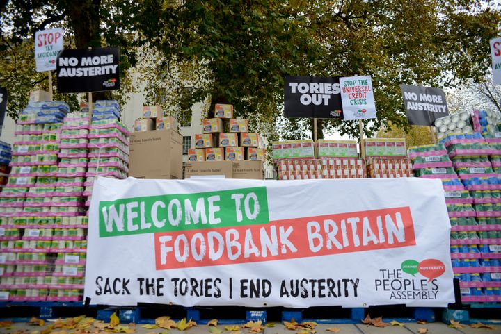 Campaigners protest against government austerity programmes next to crates of tinned food destined for food banks outside Downing Street in 2017