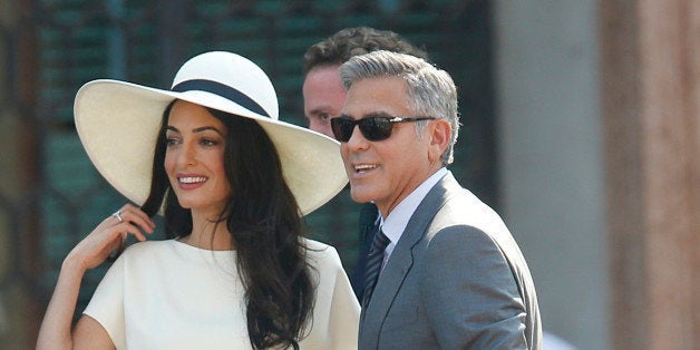 George Clooney, flanked by his wife Amal Alamuddin, arrives at the city hall for their civil marriage ceremony in Venice, Italy, Monday, Sept. 29, 2014. George Clooney married human rights lawyer Amal Alamuddin Saturday, the actor's representative said, out of sight of pursuing paparazzi and adoring crowds. (AP Photo/Luca Bruno)