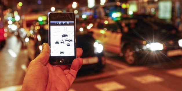 The Uber app is seen on a smartphone past cabs passing on Paseo de Gracia in Barcelona, on December 9, 2014. A judge on December 9, 2014 banned the popular smartphone taxi service Uber from operating in Spain, court officials said, following similar prohibition action in several other countries. AFP PHOTO/ QUIQUE GARCIA (Photo credit should read QUIQUE GARCIA/AFP/Getty Images)