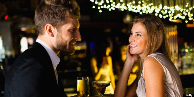 Smiling couple having drinks at bar