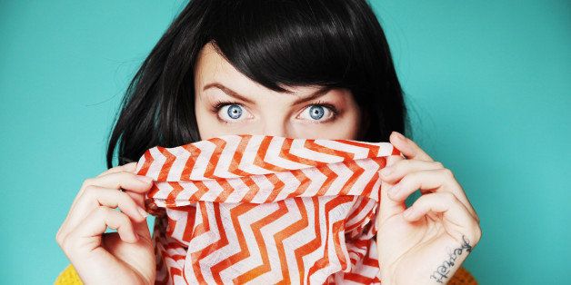 Woman holding bright scarf over lips with shocked eyes