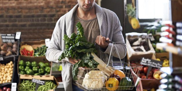Shot of a young man walking in a grocery store with a basket full of fresh produce