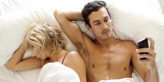 Man texting SMS on mobile phone in bed
