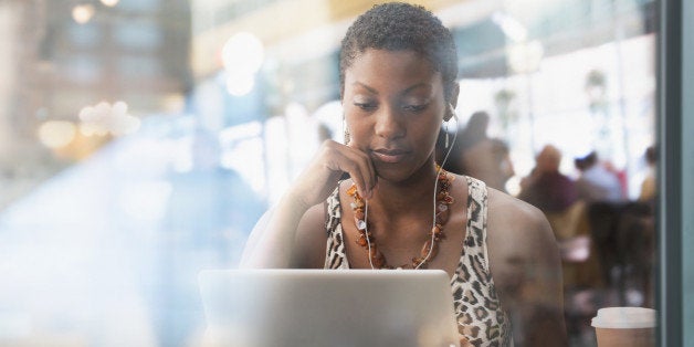 African American woman using laptop in cafe