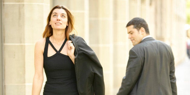 Businessman staring at woman walking on sidewalk