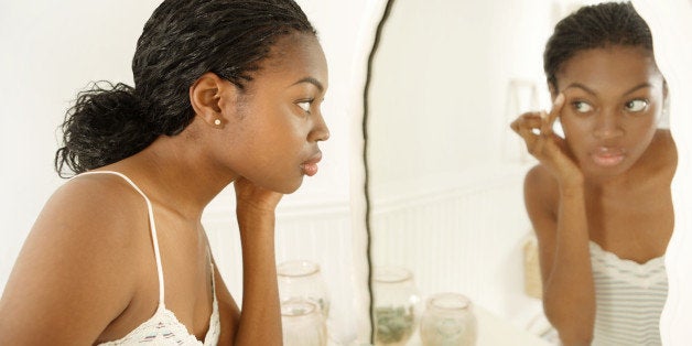 Young woman applying make-up in mirror, close-up