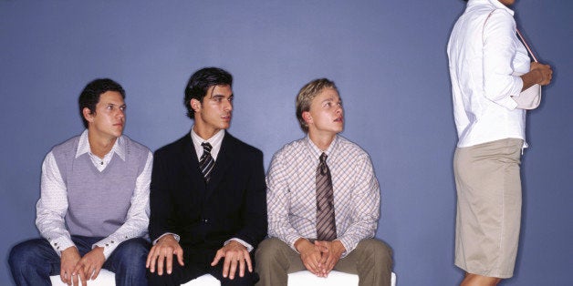 Three young men on bench indoors watching woman walking past