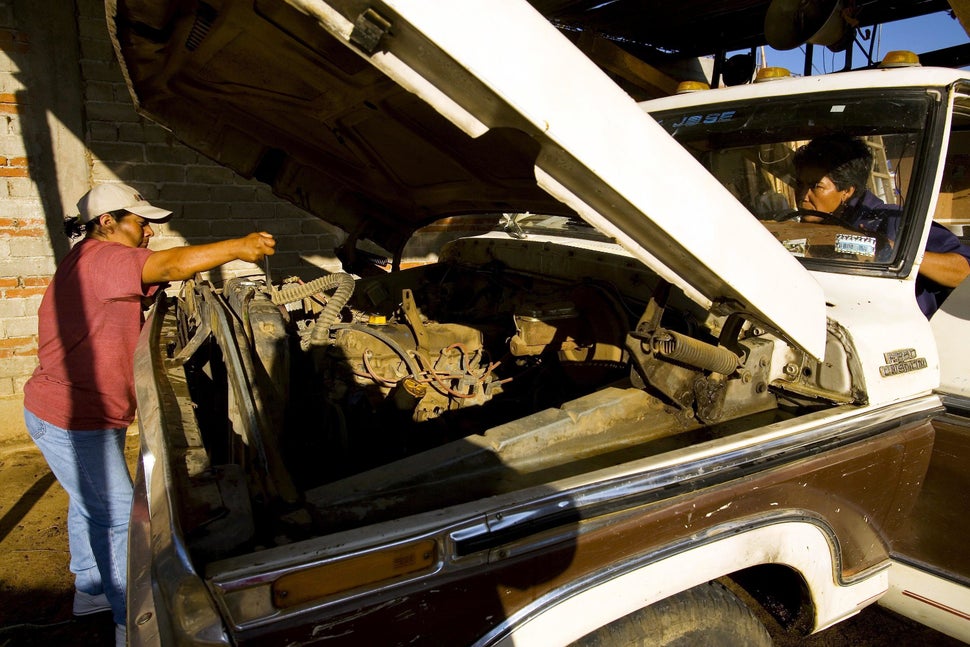 Cristina Isidro Salazar (left) and Felicitas Contreras Santiago repair their truck so they can deliver wood to construction s