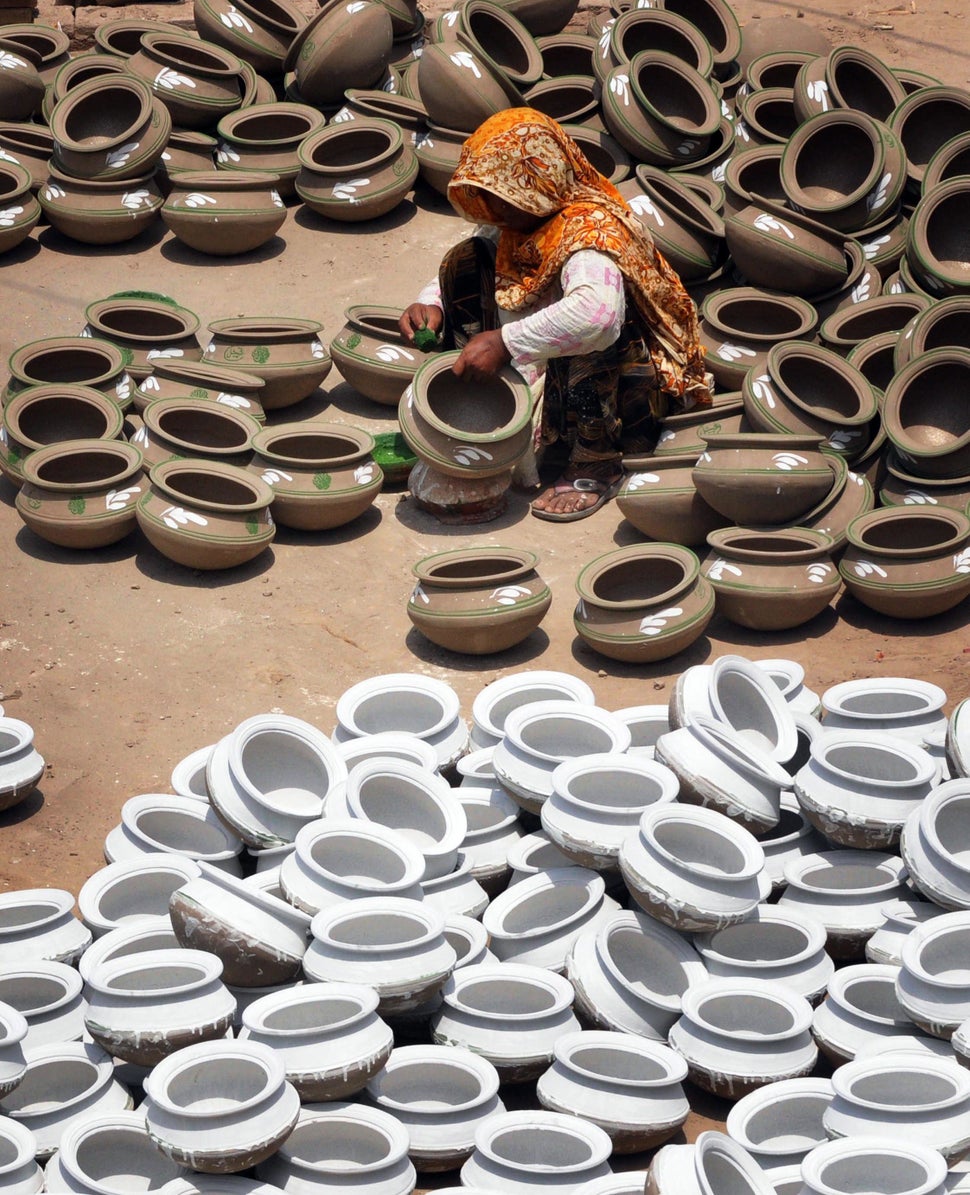 A Pakistani woman potter gives the final touches to earthen pots at a workshop on the outskirts of Lahore on June 9, 2011. (A