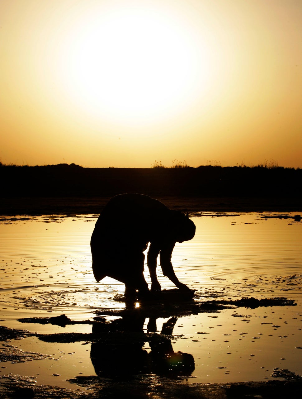 An Iraqi woman works to collect salt from a water course near Latifiyah, about 20 miles south of Baghdad, Iraq. Wednesday, Ma