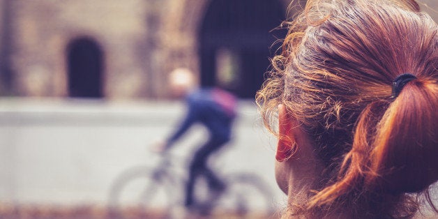 Rear view of a young woman looking at a church and a person on a bicycle