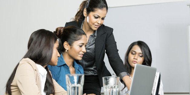 Indian women business colleagues working around a laptop