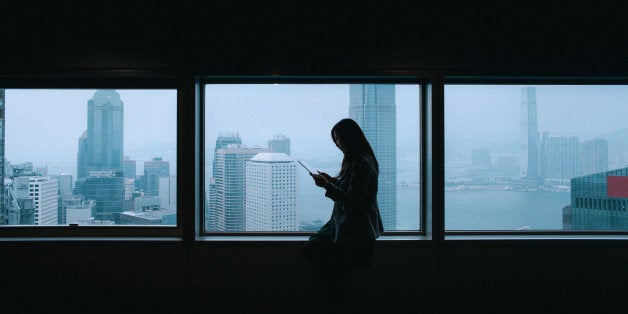 Office lady is using tablet with city view from windows at background