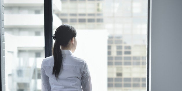 Businesswoman looking out window in empty office