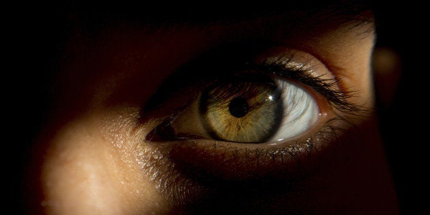 Detail of woman's eye, peering through door slat