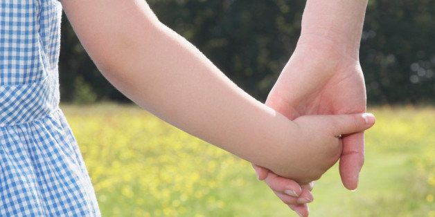 Young school girl holding mother's hand, close-up